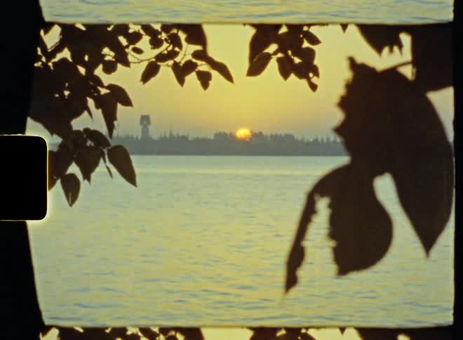Sunset over the city skyline near a river caught on vintage film