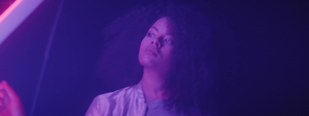 A woman is standing in a dark lit room