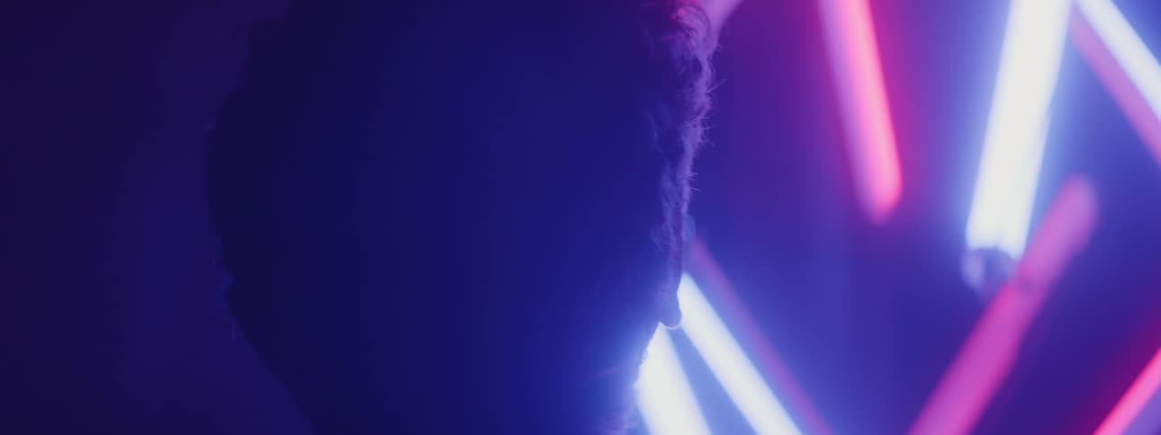 A man is looking at white and pink neon lights indoors