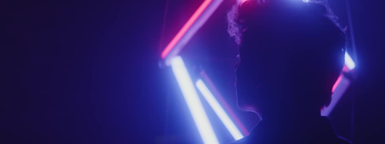A man standing in front of glowing tube lights in the dark