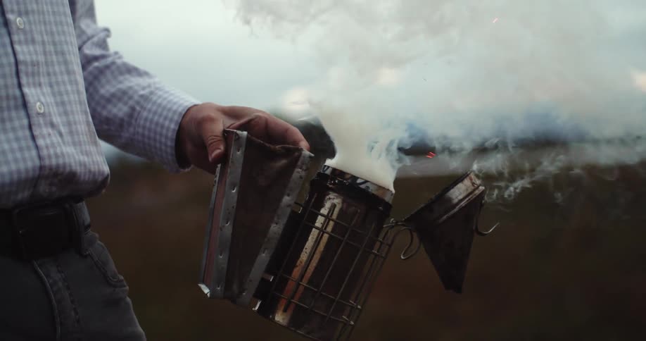 A man opens and closes a chimney starter to release smoke