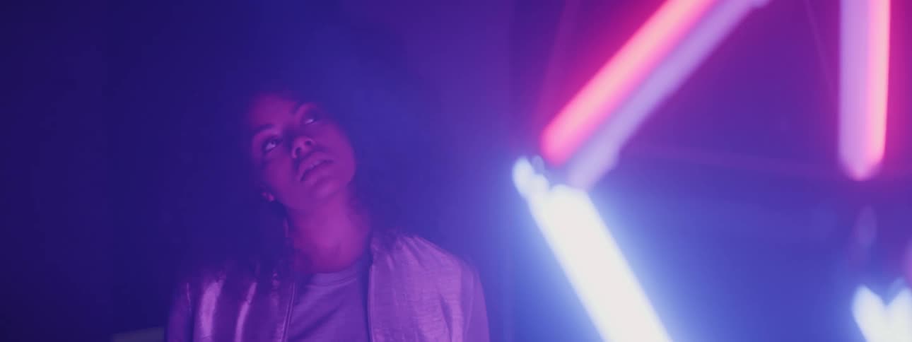 Young woman looking at hanging colorful neon lights at night