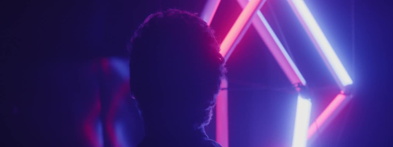 Man walks around art piece composed of glowing neon lights