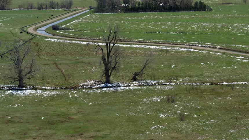 Winding country road with snow in the grass and bare trees along the roadside