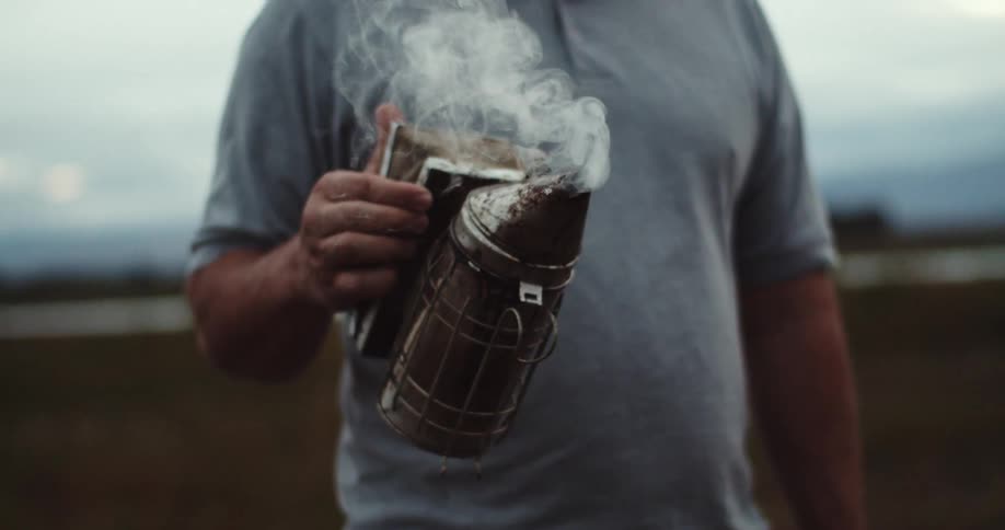 A man is standing in a field holding a smoking can