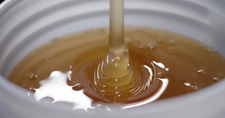 Liquid honey is being poured into a container