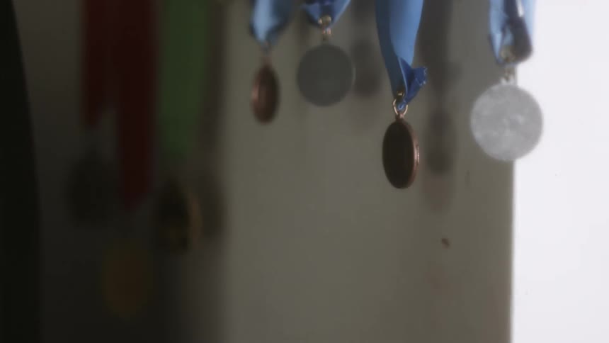 A row of medals are hanging from blue ribbons