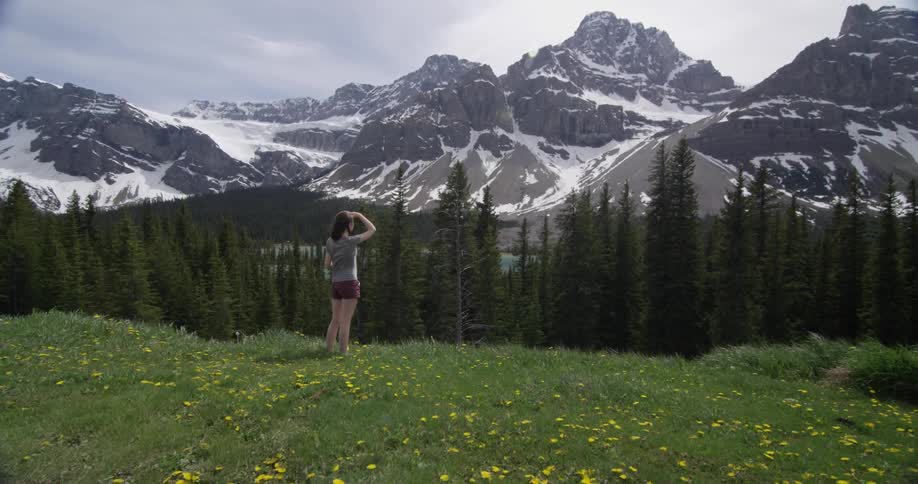 A woman looks out at a mountain and trees