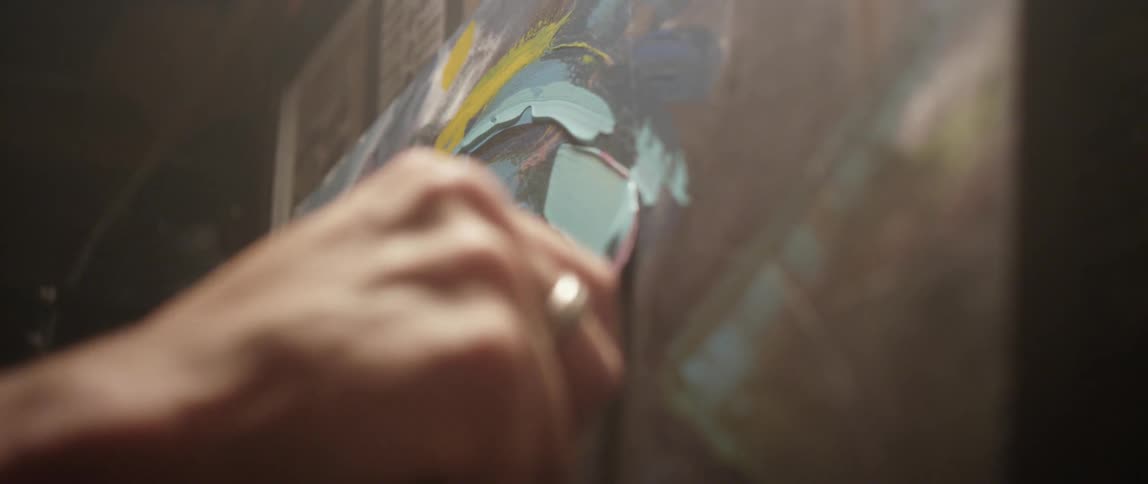 A person spreads paint on a canvas