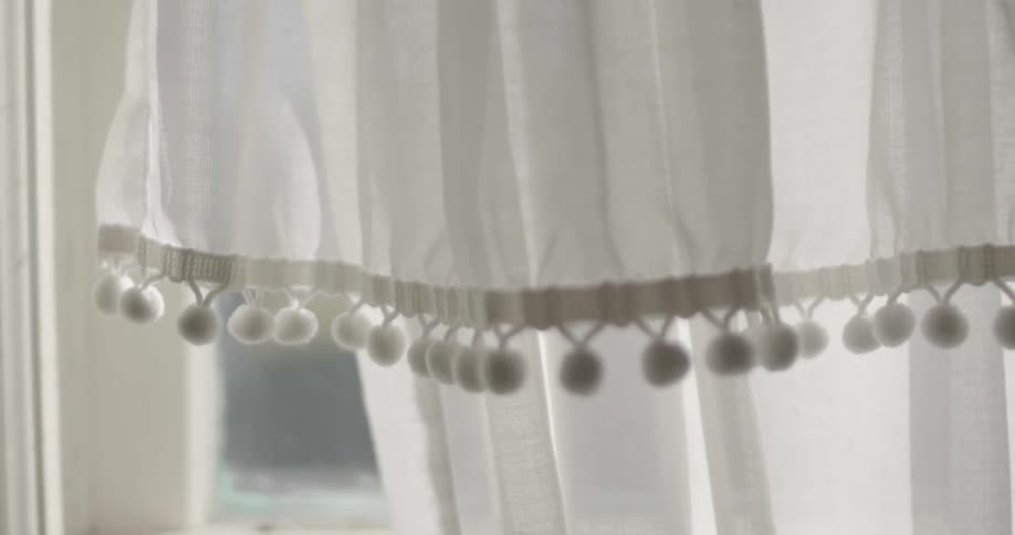 Small fabric balls decorate edge of curtains