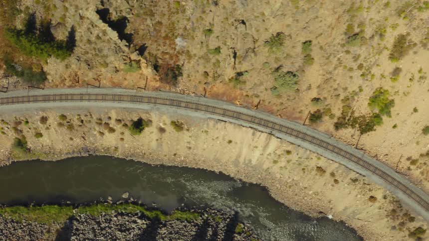 Aerial view of railroad tracks along a mountainside and a stream below