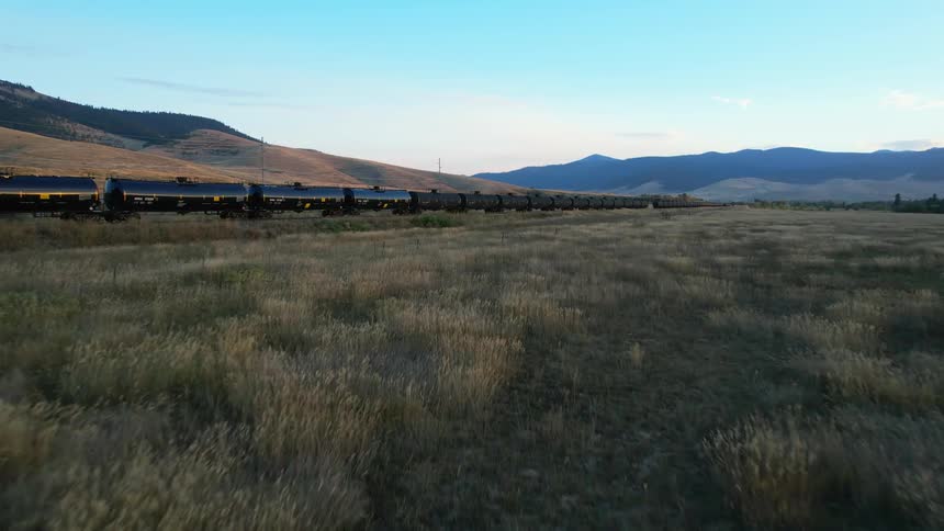 A train is moving in a rural area at dusk