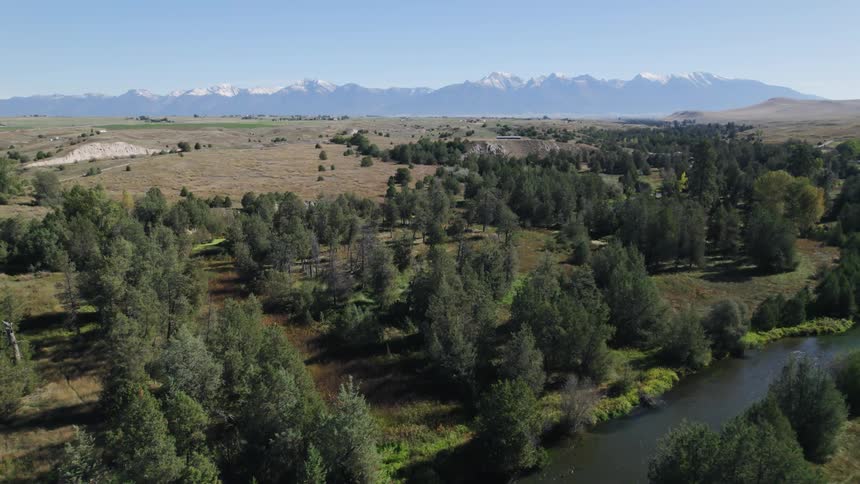 A vast countryside covered in woodland and prairie under a clear blue sky