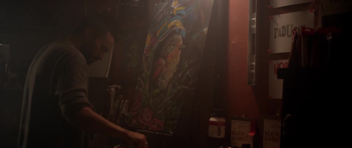 A person adjusts a painting of a bird
