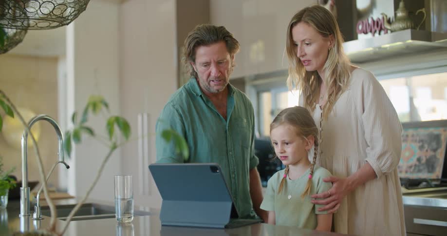 A family is in the kitchen and looking at a laptop