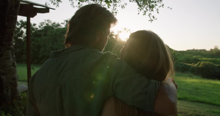 A couple hug and kiss while they watch the sun rise