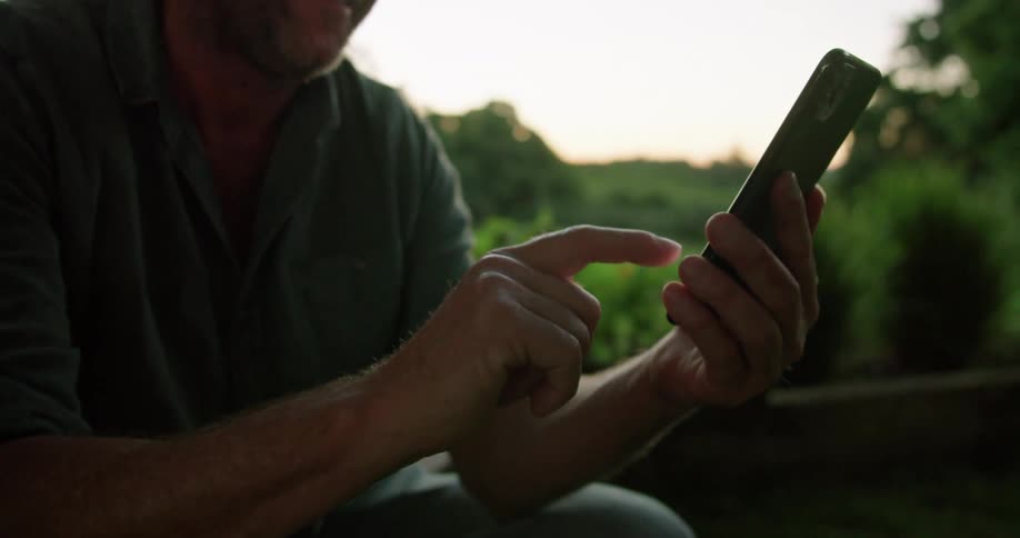 Man scrolling through social media while relaxing outdoors in nature