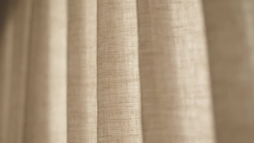 Pale gray curtains hand in folds near window