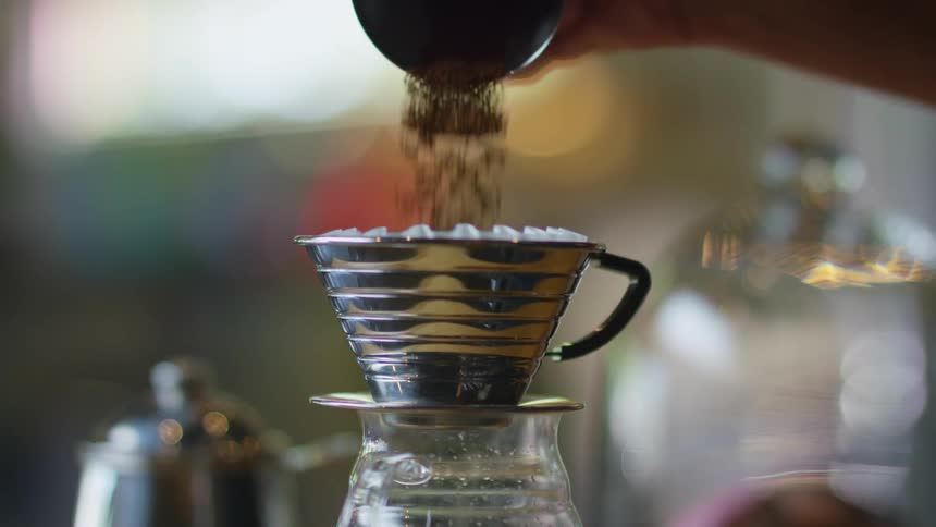 A person is pouring coffee grounds into a filter