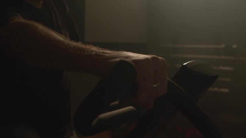 A man moves the handles of a fitness bicycle back and forth