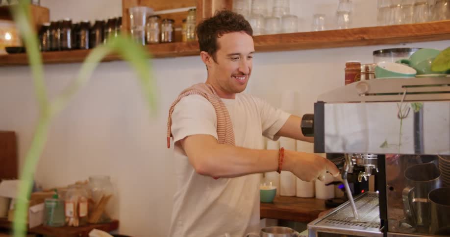 A man smiles and talks as he makes coffee for a customer