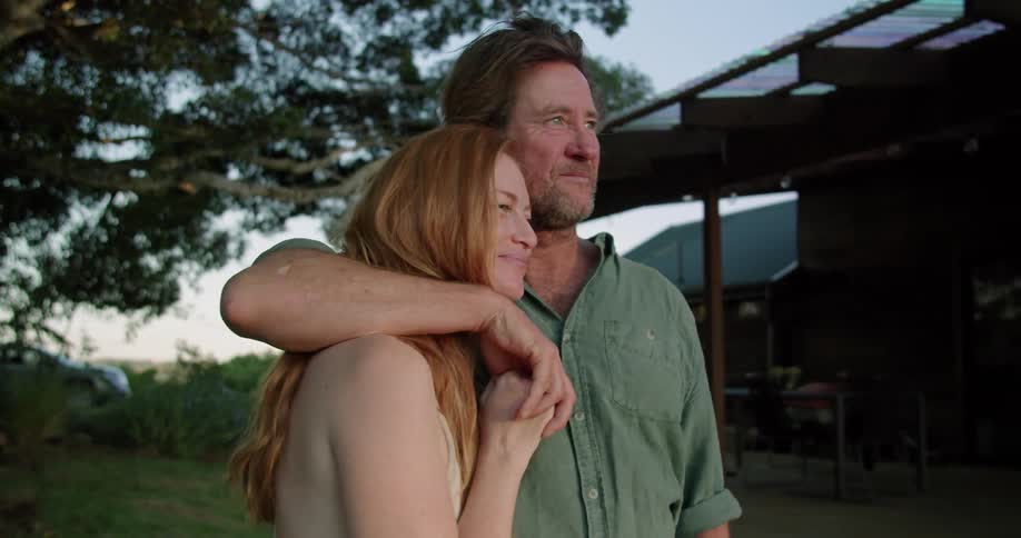 Husband and wife share a kiss outdoors at dusk