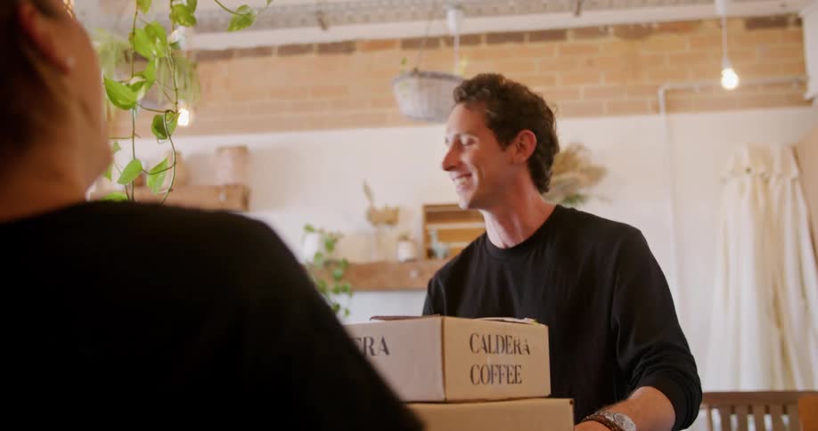 Man leaves boxes of coffee on counter then walks away waving farewell