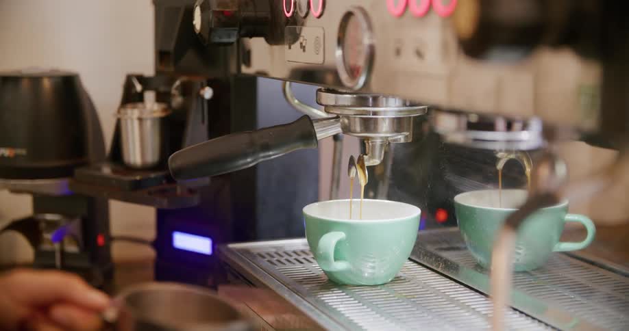 A waiter is working behind the coffee machine