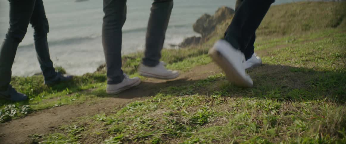 Three people are walking on the coast together