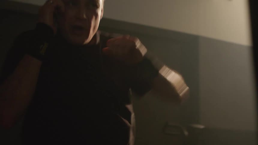 A man is boxing in a room at dusk