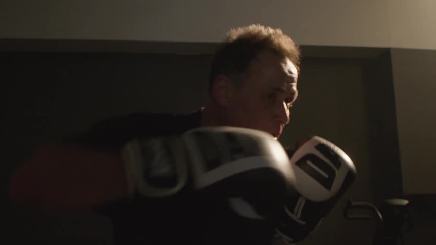 A man is punching a heavy bag in the gym