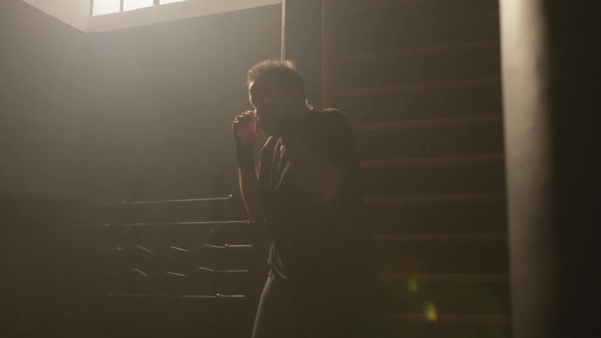 A man is practicing boxing skills indoors in an empty room