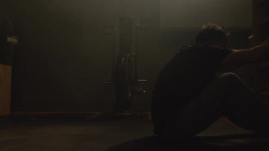 Middle aged man with black t shirt and sweatpants does sit ups in gym