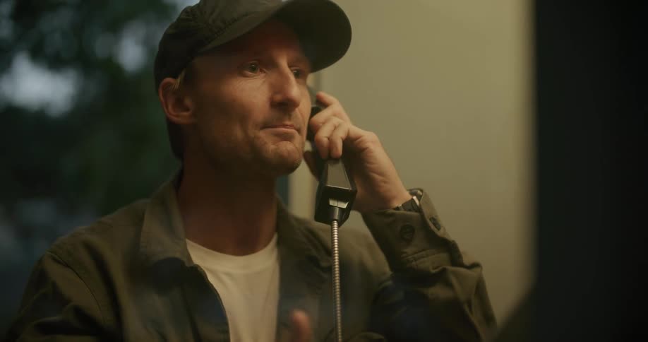 A man is talking on a telephone indoors