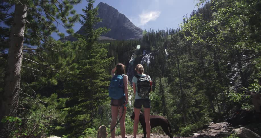Two women and a dog overlook a mountain range
