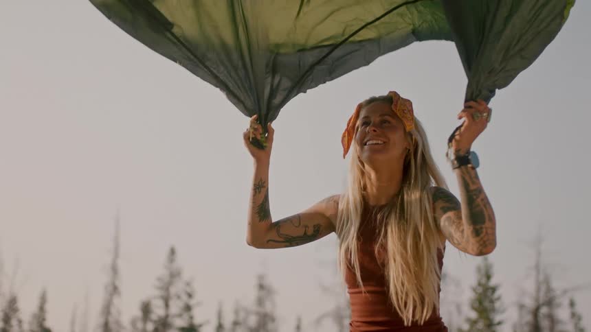 A woman laughs as she sets up a tent