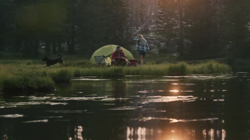 Man woman and their dog are camping in the woods