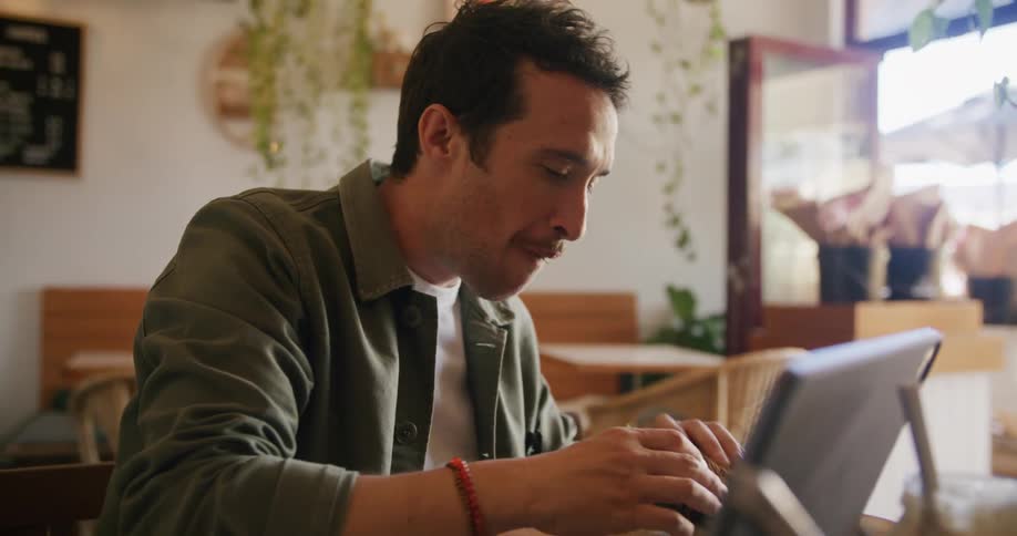 A man is eating a burger at a restaurant at midday