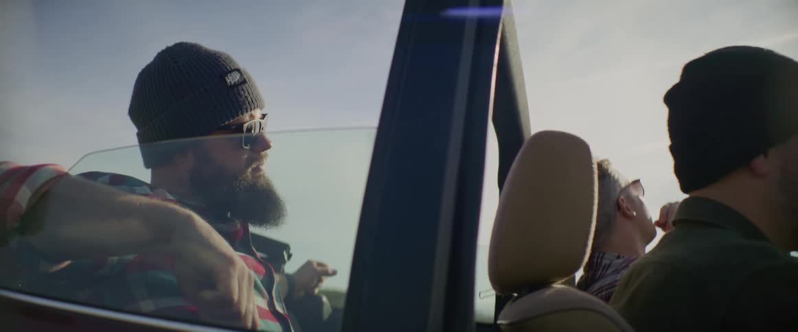 Three men sit in the car listening to music