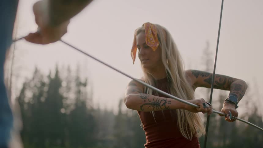 Woman helps friend put together tent frame near misty conifer forest