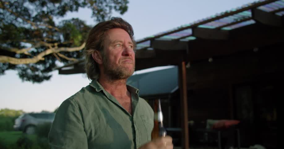 A man is standing outside drinking a bottle of beer