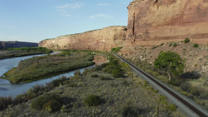 Train tracks running alongside mountains and a nearby lake