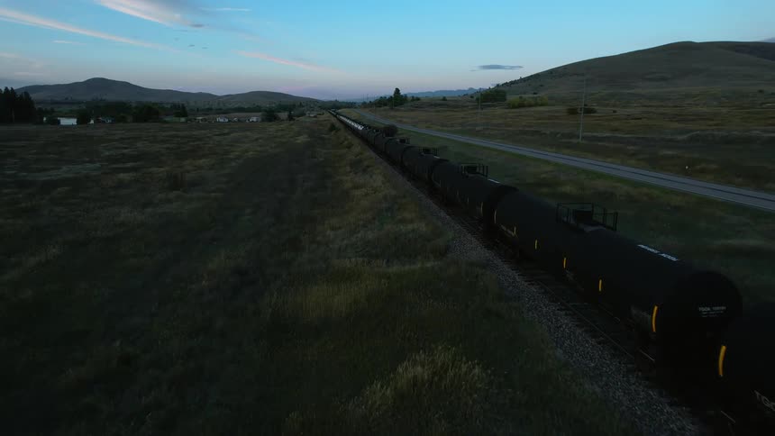 Aerial view of a freight train parked on the tracks in a field at morning