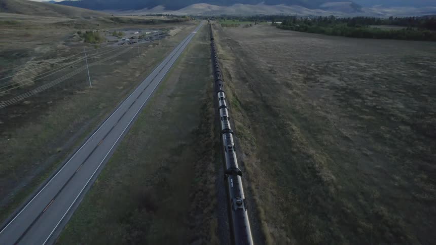 A train is moving through a rural area at dusk