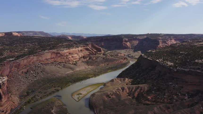 A river running along the floor of a wide canyon under a clear daytime sky