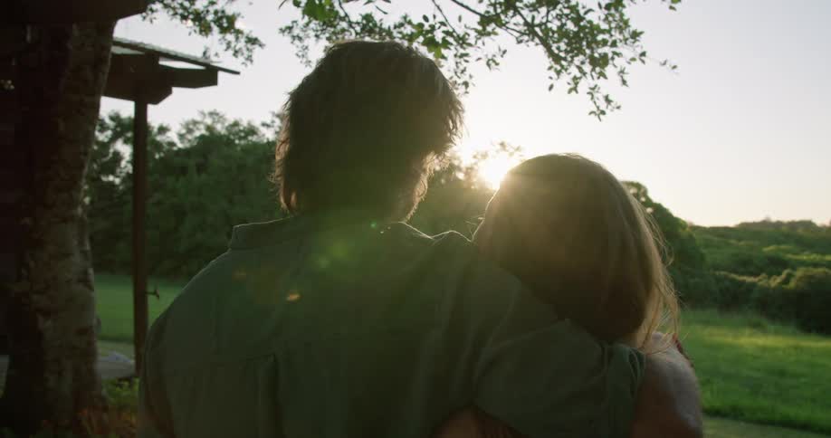 Husband and wife are hugging outdoors at dusk