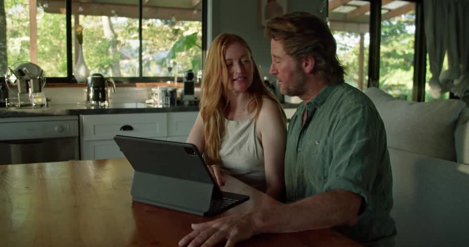 Man and woman are sitting indoors and looking at a laptop