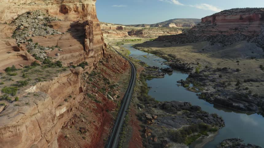 Train tracks running near a river through a canyon in the badlands mesa