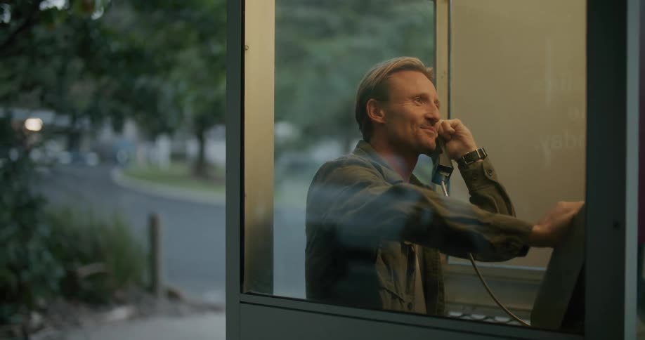 A man talks on the phone in the booth