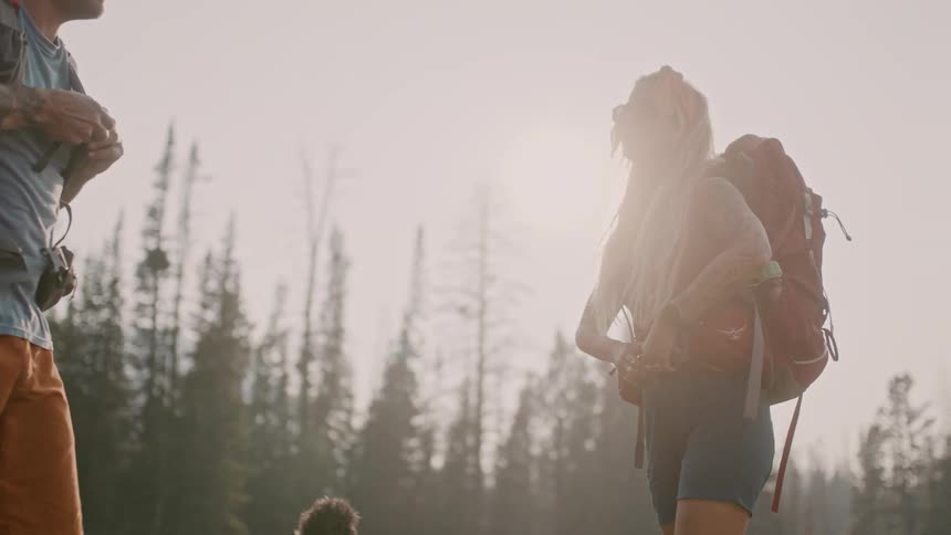 Man woman and their dog are hiking through a forest at dusk
